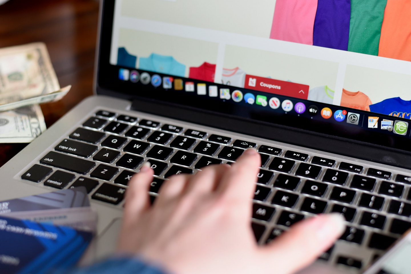 Handen typen op een zilver toetsenbord van een laptop tijdens online winkelen.